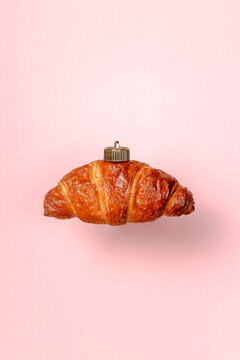Christmas bauble decoration of croissant on pink. New year concept.