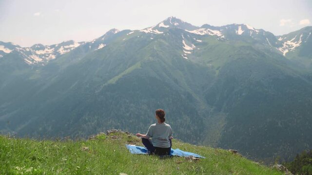 A young woman does yoga on the tops of mountains. Sports tourism