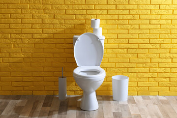 Simple bathroom interior with toilet bowl near yellow brick wall indoors. Home design