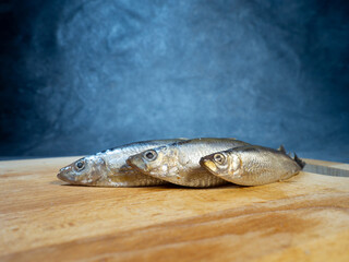 Lightly salted sprat on a cutting board. Whole small fish on the table.