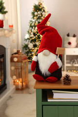 Obraz premium Cute Christmas gnome on wooden table in room with festive decorations