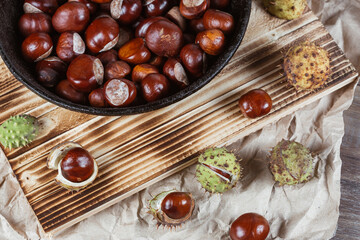 Close up view of chestnuts in a cast iron pan on a wooden background
