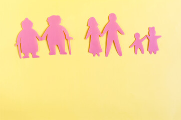 Colored cardboard figures of people of different generations on a yellow background