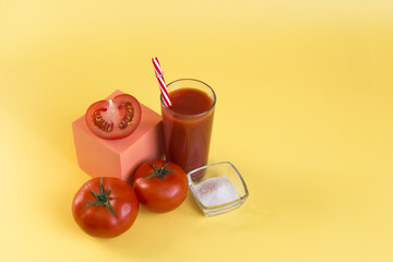 Tomato juice and tomatoes on a yellow background. Tomato juice with a red tube and red tomatoes on...