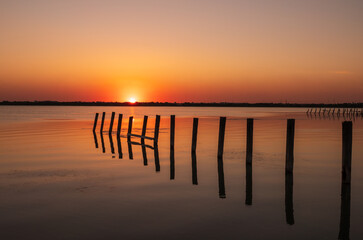 Beautiful red and orange sunset over the sea. The sun goes down over the sea. An old sea pier in orange sunset light