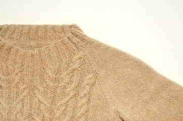 Fragment of a beige knitted sweater with a pattern on a white background. Collar, close-up.