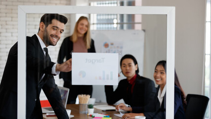 Through glass of multiethnic colleagues looking at diagrams