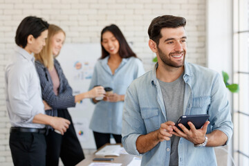 Positive businessman browsing tablet near multiracial colleagues