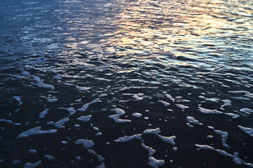 Detail of sea surface with foam during sunset