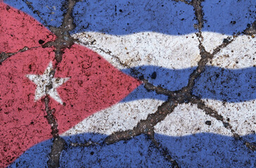 Cuba flag on cracked asphalt. The concept of crisis, default, pandemic, conflict, terrorism. Out of focus image