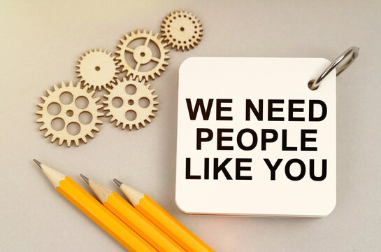 On the table are gears, pencils and a notebook with the inscription - We Need People Like You