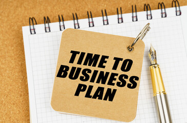 There are two notebooks and a pen on the table. On the top notepad, the inscription - Time To Business Plan
