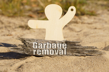 On the sand near the wooden figurine of a man there is a piece of wood with the inscription - Garbage removal