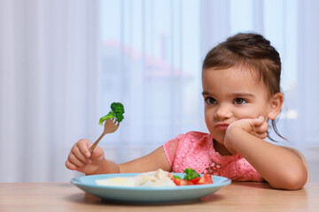 Cute little girl refusing to eat her breakfast at home