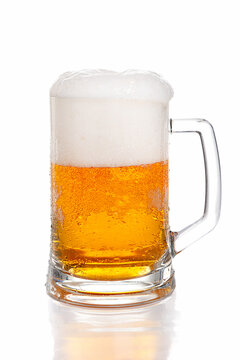 Light beer with thick head of foam in glass beer mug on white background