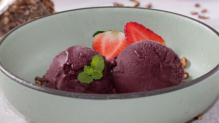 Frozen Açaí and ripe strawberries in a bowl, selective focus.