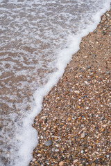 Blurred defocus background. Summer landscape with the sea. Light wave and pebbles