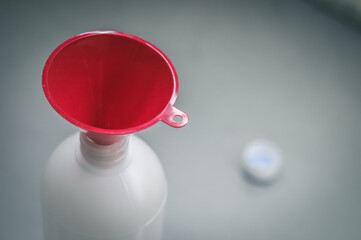Red funnel in a plastic bottle. Selective focus, copy space
