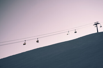 Ski lift above ski slop in resort during sunset