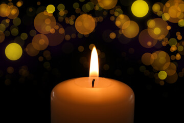 Wax candle burning in darkness, bokeh effect. Christmas Eve