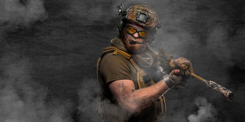 A special forces soldier during a special operation in smoke against a dark concrete wall.