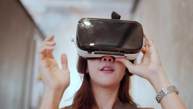 asian programer female woman wearing vr goggle 3d visualization walking and exploring in metaverse futuristic lifestyle in modern office background,new normal technology virtual digital world explore 