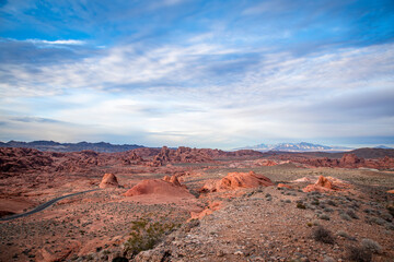 Fototapeta na wymiar An empty road leads through the desolate landscape of Valley of Fire State Park in Utah during the early stages of sunset.