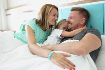 Happy cheerful whole family hugging in bed together in morning
