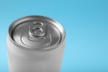 Can of energy drink on light blue background, closeup. Space for text