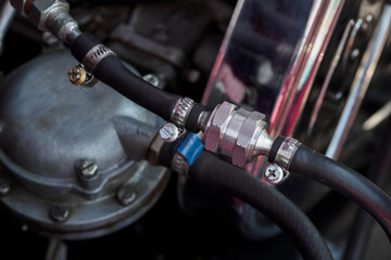 Reversing valve on hose with metal clamps at car engine veteran.