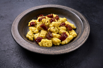 Close up potato gnocchi with parmesan and dried tomatoes in ceramic plate, low key