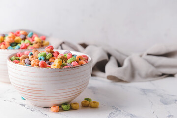 Bowl with crunchy corn flakes rings on light background