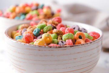 Bowl with crunchy corn flakes rings on light background, closeup