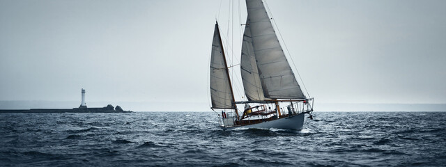 Old expensive vintage two-masted sailboat (yawl) sailing in an open sea during the storm. Reefed...