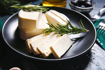 Plate with delicious feta cheese on color background
