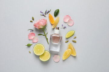 Flat lay composition with bottle of perfume and fresh citrus fruits on light grey background