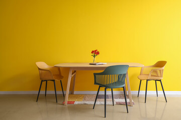 Dining table with flowers and magazine near color wall