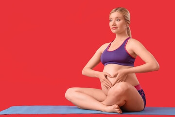 Young pregnant woman relaxing on red background