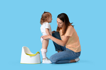 Mother potty training her little daughter on color background