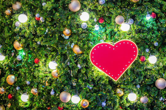 Merry x-mas,Close up of heart shaped space Colorful balls ,gifts box and Christmas greeting picture parcel decoration on Green Christmas tree background Decoration During Christmas and New Year.