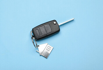 Car key with keychain in house shape on blue background