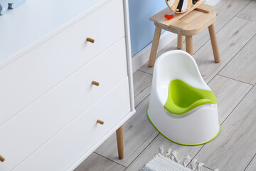 White potty near chest of drawers on grey wooden floor