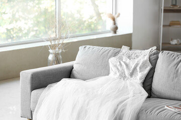 Elegant wedding dress on sofa in living room