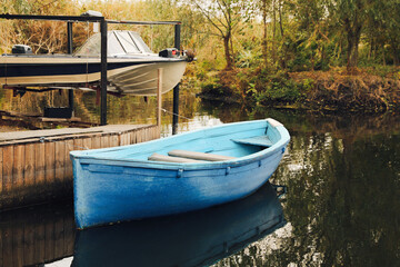 Naklejka na ściany i meble Light blue wooden boat on lake near pier