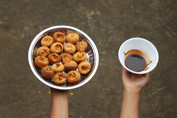 Homemade Pani puri or golgappa which is an Indian snack on a plate with tamarind sauce held in hand...