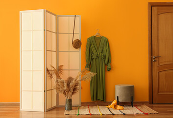 Interior of stylish room with folding screen and dress