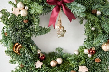 Fototapeta na wymiar Beautiful festive wreath of fresh spruce on Gray wall. Xmas circlet with ornaments and balls. Christmas mood.