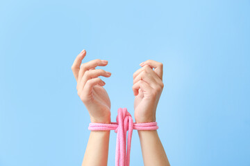 Woman with tied together hands on color background