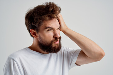 Obraz premium bearded man in a white t-shirt headache migraine problems light background