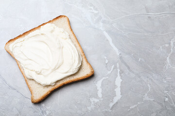 Slice of bread with tasty cream cheese on light grey marble table, top view. Space for text